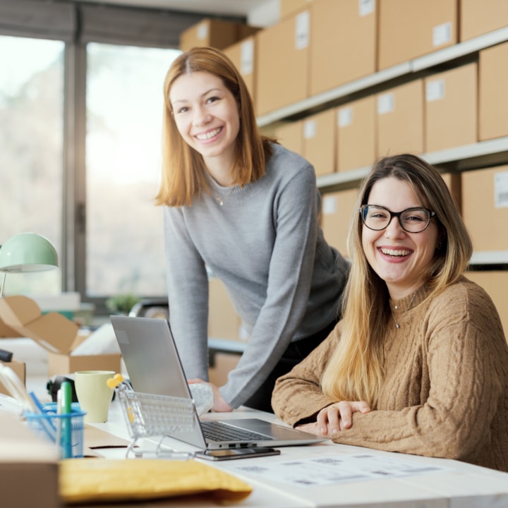two females looking at a computer, surrounded by boxes